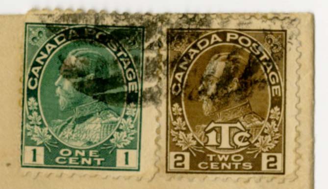 Close up of the two stamps from the envelope, one is green and one is light brown. Both have King George V's face on it.